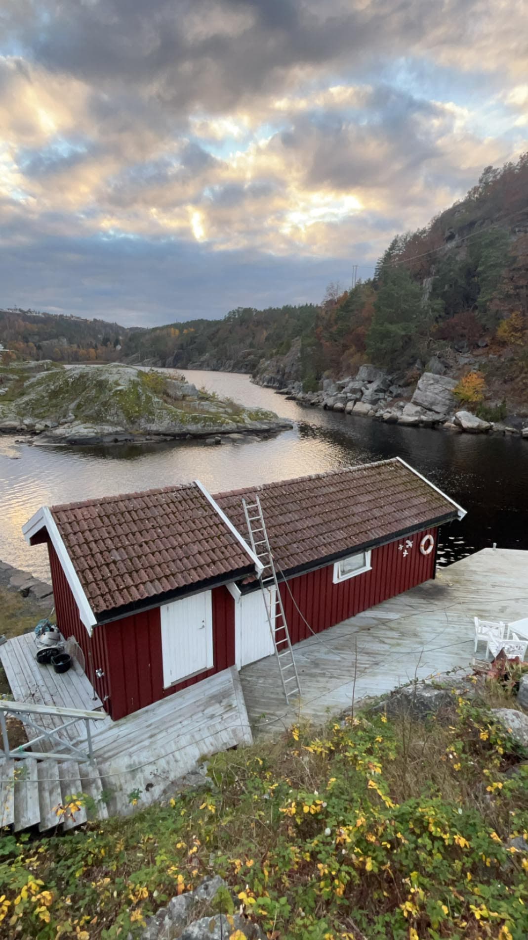 Sjøhus med tegltak ved vannet i kveldslys